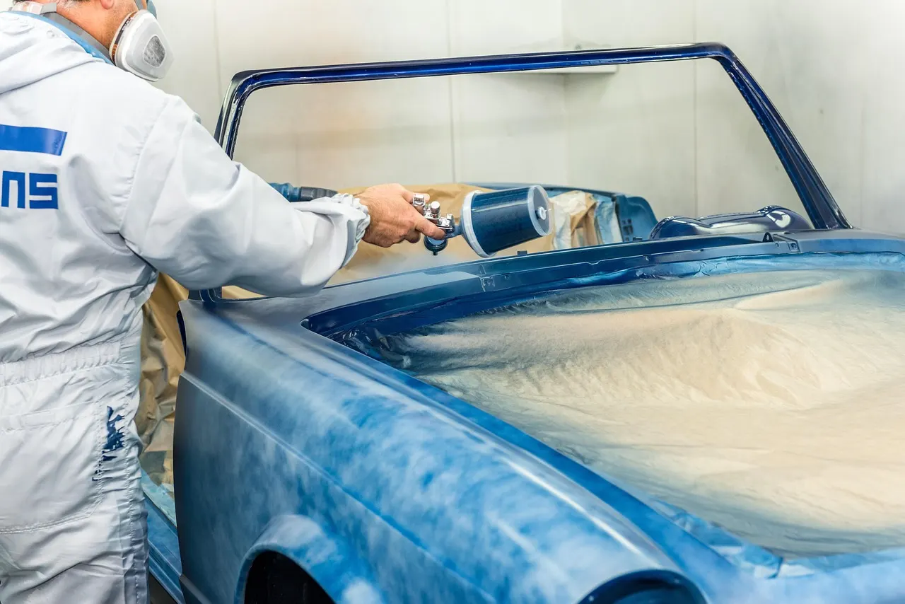 Painter spraying a car in a spray booth